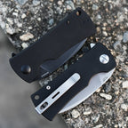 SHOOZIZ HAN306-BGS and BGB folding knives closed on stone, featuring satin and black PVD blades with black G10 handles.