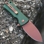 SHOOZIZ HAN306-GMRG folding knife open on stone, 14C28N steel with rose gold PVD, green Micarta handle.