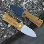 SHOOZIZ HAN306-JUS and JUB Ultem folding knives open on stone, showing satin and black PVD 14C28N steel blades.
