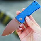 SHOOZIZ HAN306-LMRG folding knife close-up in hand, rose gold PVD 14C28N steel blade with blue Micarta handle.