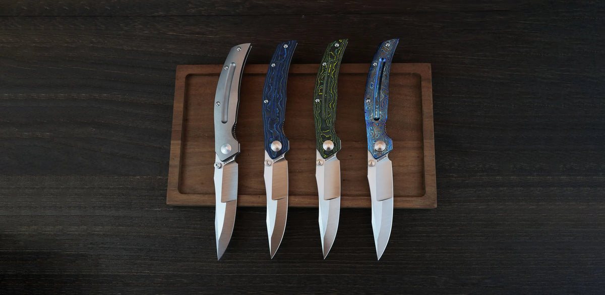 SHOOZIZ SERPENT series lineup on a wooden tray, featuring ELMAX steel blades with titanium, blue carbon fiber, yellow carbon fiber, and zirconium Damascus handles.