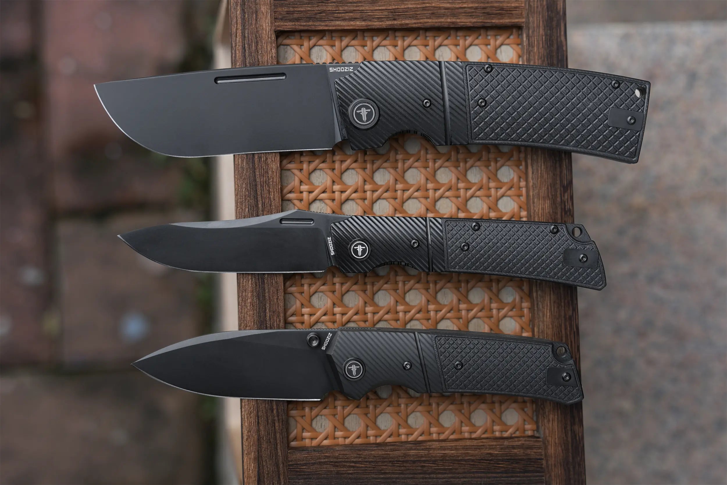 Background image for SHOOZIZ slide to reveal your design section, featuring three black tactical EDC folding knives: XUN122-BGB, XUN123-BGB, and XUN125-BGB. Demonstrating rugged handle and blade finish configurations engineered to one uncompromising standard.