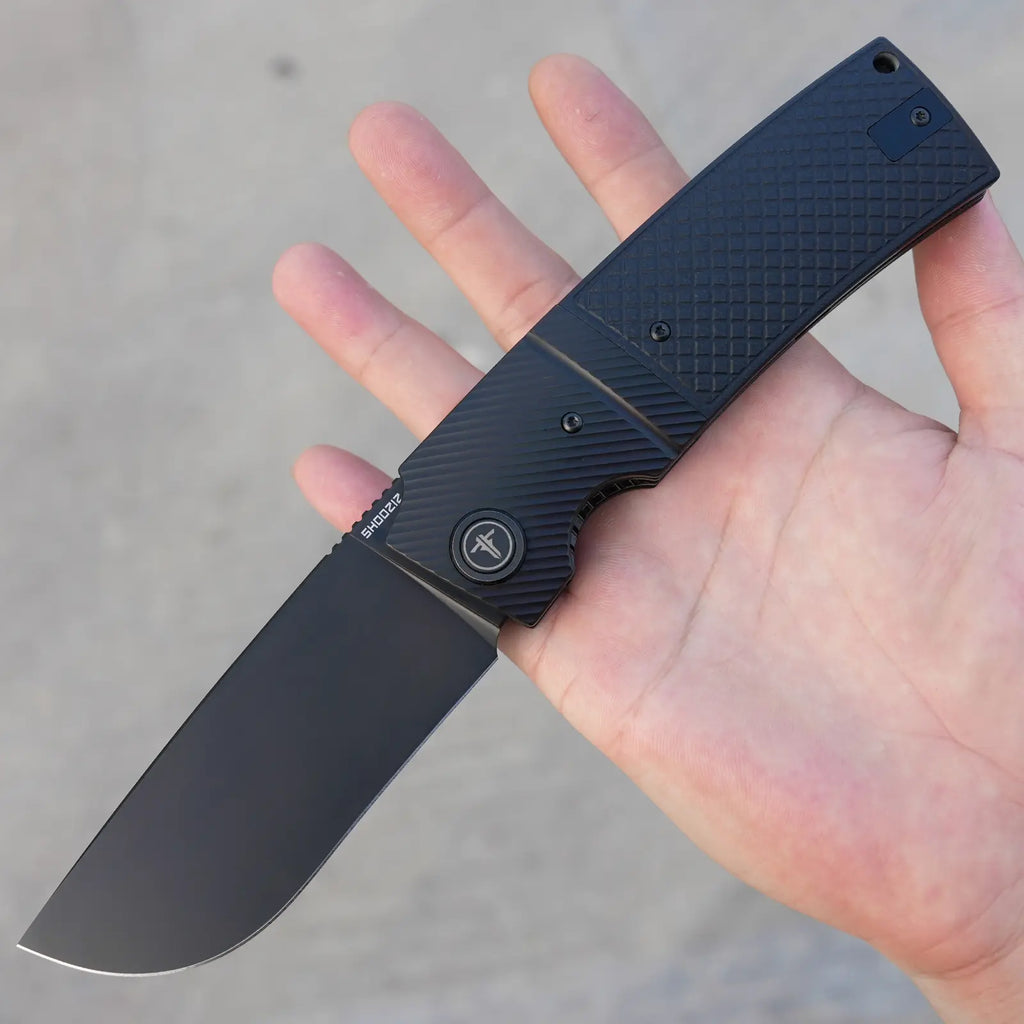 SHOOZIZ XUN122-BGB black PVD folding knife held in hand close-up, black G10 handle, black steel bolster.