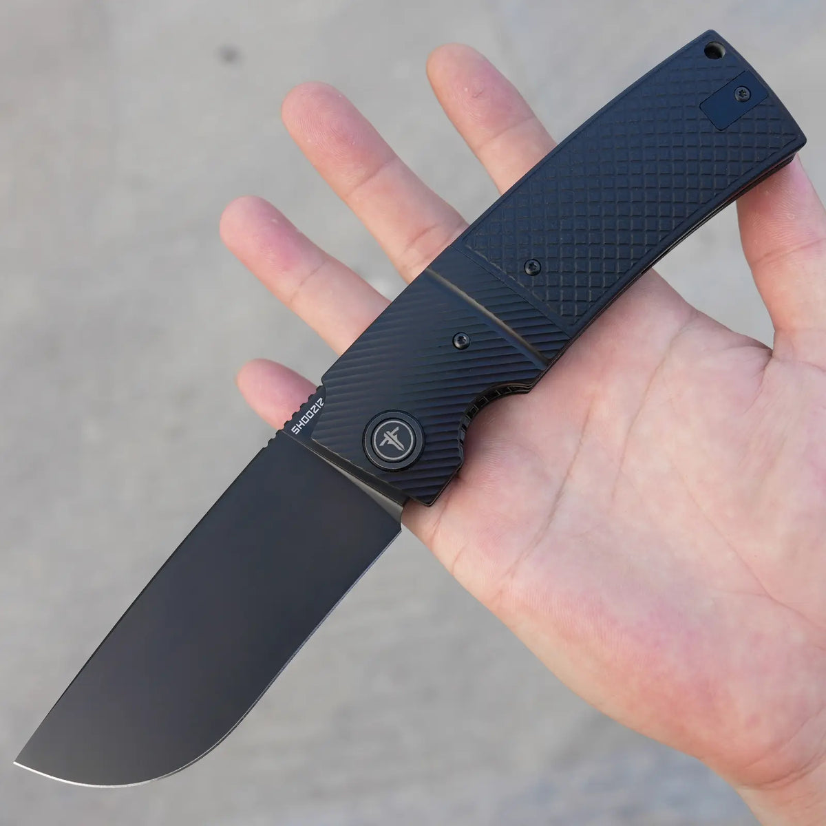 SHOOZIZ XUN122-BGB black PVD folding knife held in hand close-up, black G10 handle, black steel bolster.