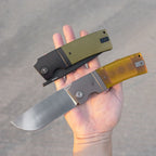 SHOOZIZ XUN122-GGB black PVD closed and XUN122-JUS satin open held in hand, green G10 and Ultem handles.