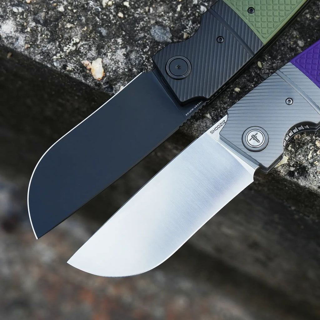 SHOOZIZ XUN122-GGB black PVD and PGS satin folding knives open on stone, green and purple G10 handles.