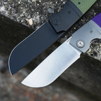 SHOOZIZ XUN122-GGB black PVD and PGS satin folding knives open on stone, green and purple G10 handles.
